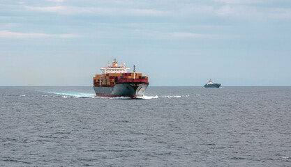 Container cargo ship full loaded in wavy sea reaches the port. Import export, water transport.