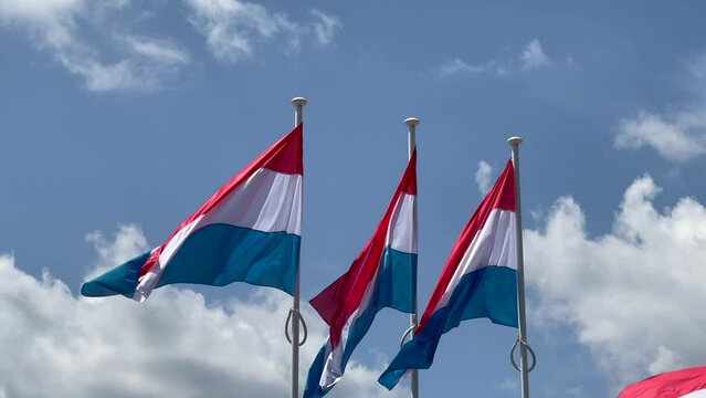 Three Luxembourg flags waving in the wind on a bright sunny summer day