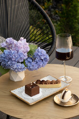 Macaroon, cake with shortcrust pastry, mousse cake with coffee in wineglass on a wooden cafe table in terrace