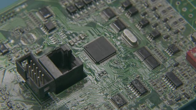 The hand applies the paste with a cotton swab to the chip on the electronic board