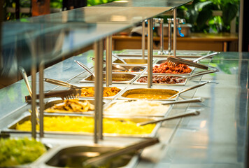 Asian food buffet in restaurant multiple food dishes and salad.
