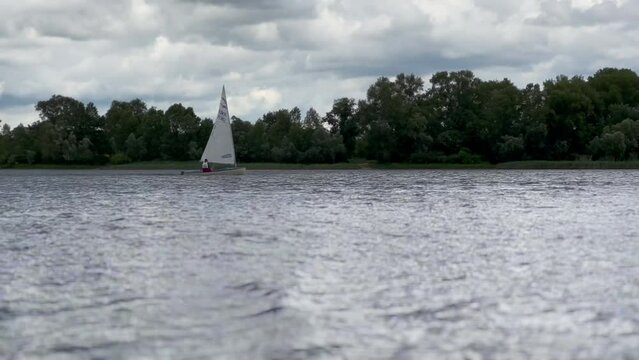 A sailboat on the Dnipro River. Regatta on a sunny day. A white sailboat sails with the wind. Sunny day. Tailwind on the river. High quality 4k footage