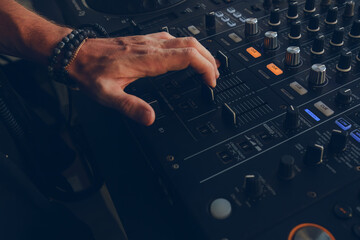 DJ's hand on the mixing console. Close-up.