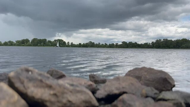 A sailboat on the Dnipro River. Regatta on a sunny day. A white sailboat sails with the wind. Sunny day. Tailwind on the river. High quality 4k footage