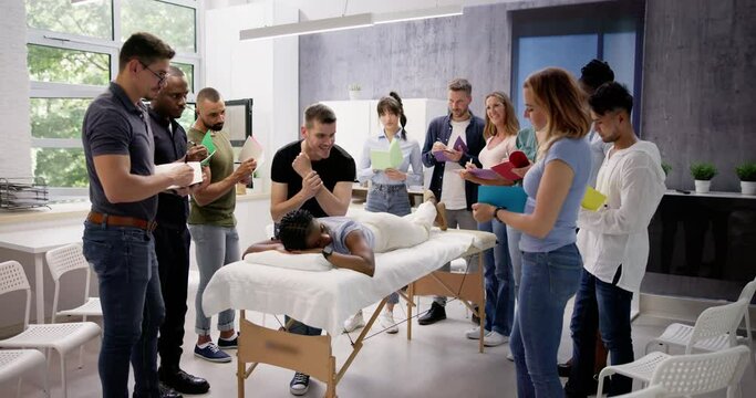 Male Instructor Teaching Massage Technique To Group