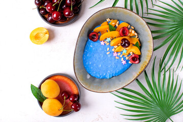 Blue rice porridge with spirulina, apricot, cherry and pine nuts in the ceramic bowl. Healthy breakfast. Top view