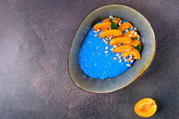 Blue rice porridge with spirulina, apricot and pine nuts in the ceramic bowl. Healthy breakfast....