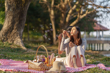 In love couple enjoying picnic time blow soap bubbles in park outdoors Picnic. happy couple relaxing together with picnic Basket.
