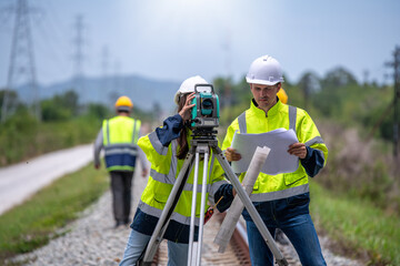 Fototapeta Surveyor engineers team wearing safety uniform,helmet and blueprint document checking inspection by theodolite to measurement position on railway construction site is industry transportation concept. obraz
