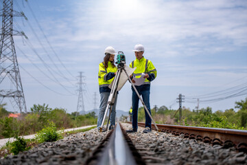 Surveyor engineers team wearing safety uniform,helmet and blueprint document checking inspection by theodolite to measurement position on railway construction site is industry transportation concept. - obrazy, fototapety, plakaty