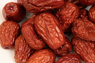 Dried jujube seeds which are brown overlay on a white background. Jujube seeds is an ingredient in desserts, soups and drinks. Close-up 