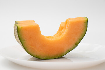 Orange melon or Japanese melon on a white palette on white backgrounds. Sliced melon ready to serve.