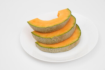 Orange melon or Japanese melon on a white palette on white backgrounds. Sliced melon ready to serve.