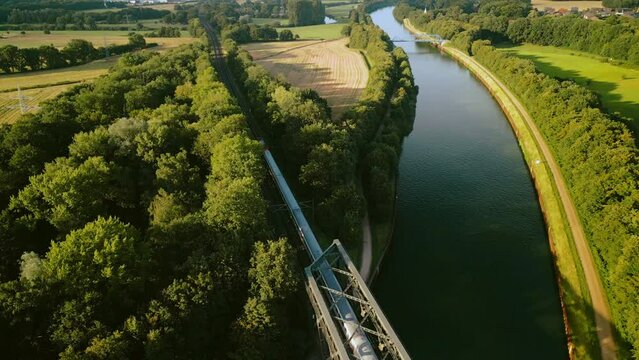 Regional train crossing a river bridge in sunny Sumer day, aerial footage