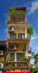 Fototapeta premium Old Apartment house block in Hanoi Old Quarters Vietnam narrow tall houses with plants on exterior of the building colourfully decorated 