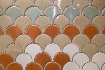Texture of ceramic fish scale mosaic tiles in earth tone palette, elegant fan shaped pattern for bathroom backsplash or kitchen wall interior design, decorative mediterranean style textures © Nutyuwan