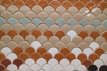 Background of colorful ceramic fish scale mosaic tiles in earth tones, elegant fan shaped pattern for bathroom or kitchen wall interior design, decorative mediterranean style textures © Nutyuwan