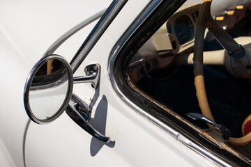 Chrome rearview mirror on a white retro car. Close-up.