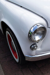Obraz na płótnie Canvas Chrome headlight on a white retro car. Close-up.