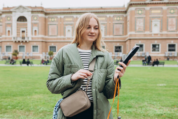 Young blonde woman listening to audio guide at the Vatican Museums in Rome, Italy