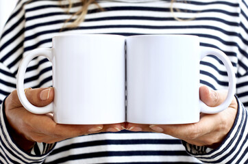 Girl is holding white 2 mug in hands. Blank  front - back cups mockups