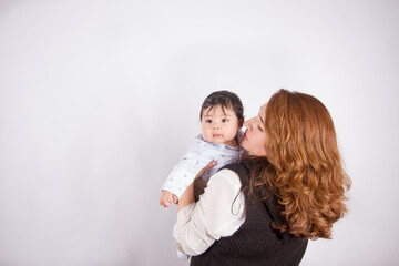 Beautiful photo of loving mom with baby on light photo studio background. Family and baby concept.