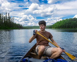 Man on a canoe with a moose in the background