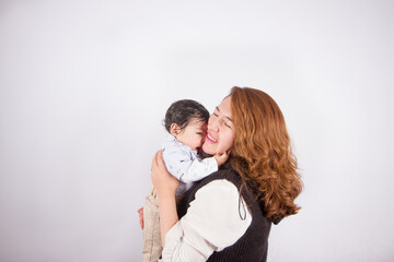 Beautiful photo of loving mom with baby on light photo studio background. Family and baby concept.
