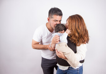 Beautiful photo of Dad and mom being affectionate with baby on light photo studio background. Family and baby concept.