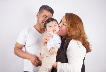 Beautiful photo of Dad and mom being affectionate with baby on light photo studio background. Family and baby concept.