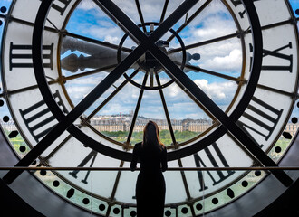 A girl standing in front of a huge clock overlooking a city