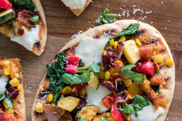 Homemade summer garden pizza on grilled naan bread, ready for eating.