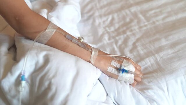 Close-up shot of IV infusion in hand of female patient in hospital.