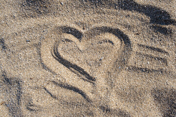 Fototapeta na wymiar Drawing heart shape love concept on sand at the beach with vacation holiday summer travel background. Heart shape and footprint on sand.