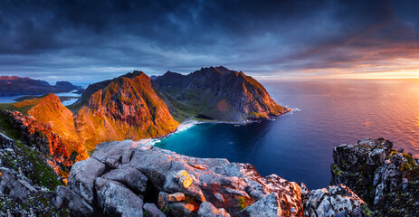 Aerial view of rocky shoreline at sunrise with mountains and cliffs