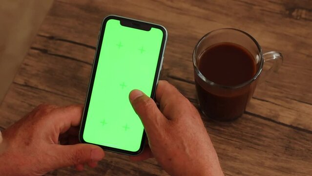 Man's hand scrolling smartphone green screen chroma key hands cup of coffee