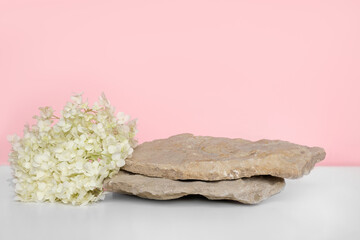 Stone Podium with flowering hydrangea branches for product presentation. Abstract minimal natural rock pedestal on pink background. Showcase, white flowers soft shadow. Scene, display case. Front view