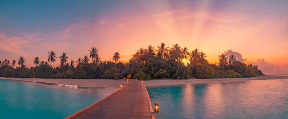  Beautiful sunset beach coast. Colorful sky clouds sun rays over palm trees silhouette. Panoramic island landscape, calm sea reflections relax tropical paradise. Wooden pier path led lights in resort © icemanphotos