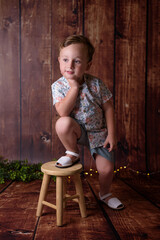 Portrait of sitting boy, isolated on wooden background