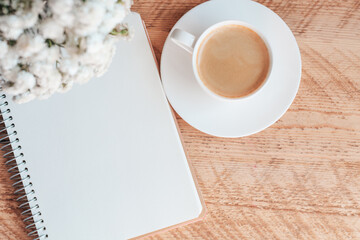 Morning cup of coffee with paper notepad on wooden table. Morning coffee mug for breakfast, empty notebook with vintage filter effect. copy space. planner mockup. Cozy work space