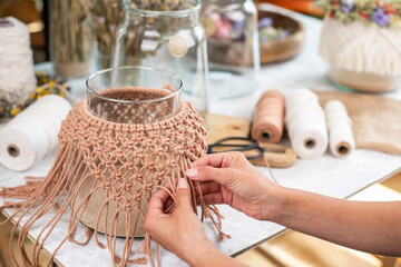 Frau knotet Makramee Muster an eine Glasvase, Windlicht Dekoration mit macrame, Knoten knüpfen