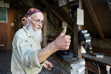The old caretaker of the cave stands at its entrance and raises his thumb up in approval