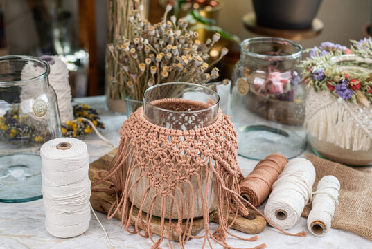 Windlicht aus Glas mit Makramee dekoriert auf einem Basteltisch