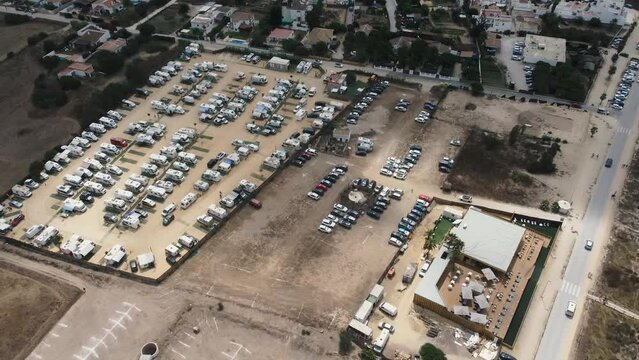 Toma a&eacute;rea en 4k de aparcamiento en terreno arenoso lleno de coches y caravanas en la costa de cadiz