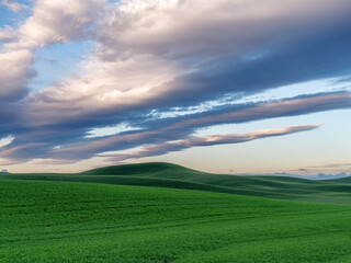 Colored clouds over a green field