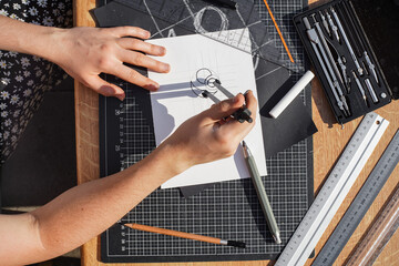 Architect and designer working accurately on a project drawing sketches and technical drafts on paper using professional tools like rulers compass and triangle logo design top view over the shoulder