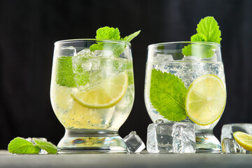 Close-up of two glasses of mojito cocktail with ice cubes on a dark background. Low angle view. Studio shot.