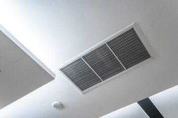 Ceiling mounted cassette type air conditioner and modern lamp light on white ceiling. Duct air conditioner for home, hall or office.