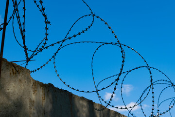 barbed wire on a concrete fence. concept prison, border, penetration, protection.