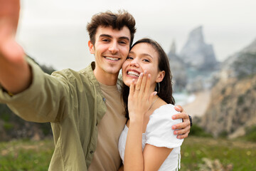 Unforgettable proposal on the beachfront. Happy couple embracing and taking selfie after engagement - obrazy, fototapety, plakaty